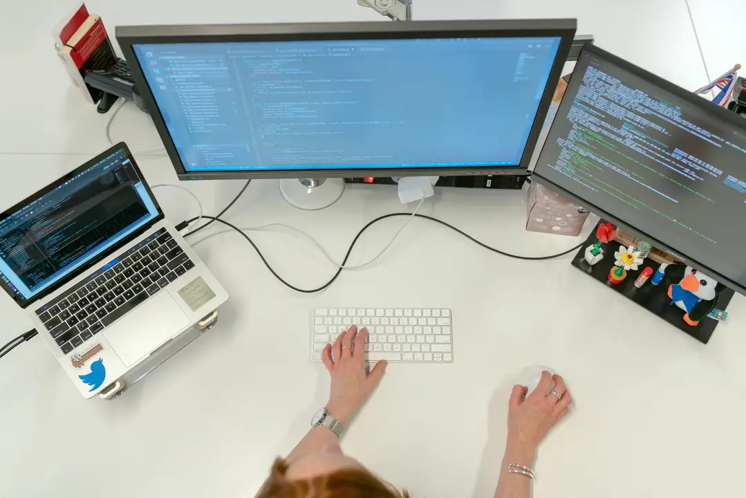 Mployees sitting at a table using laptops to complete work tasks