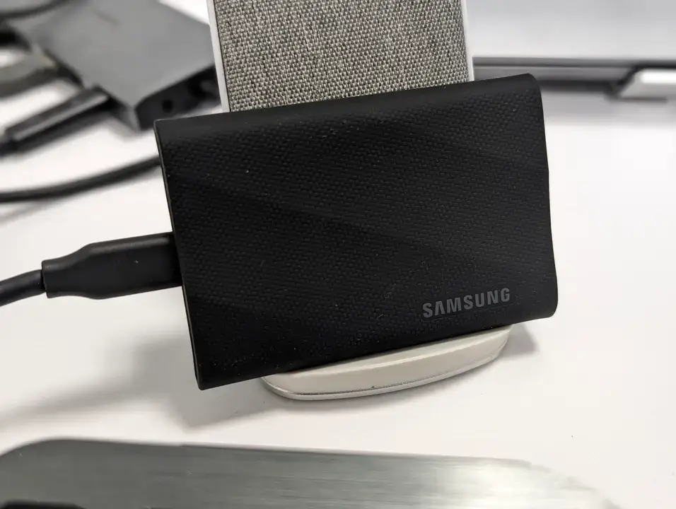 Straight-on product photograph showcasing the Samsung Portable SSD T9 external solid state drive device with its sleek, compact rectangular design and black ridged rubber frame.