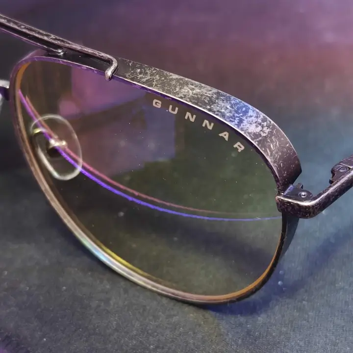 Close-up of GUNNAR glasses lens and frame showing logo detail on the lens