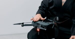 Autonomous Drone AI Lets Small Drones Identify and Attack Targets on the Battlefield | Smart Tech, Sharp Takes - CRYOVEX.com Person in a black robe handling a drone on lap in a studio setting.