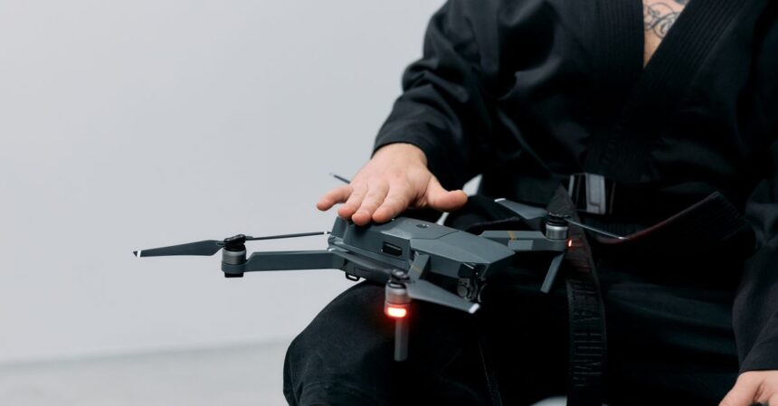 Autonomous Drone AI Lets Small Drones Identify and Attack Targets on the Battlefield | Smart Tech, Sharp Takes - CRYOVEX.com Person in a black robe handling a drone on lap in a studio setting.