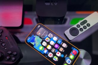 Stylish home entertainment setup featuring an iphone, apple tv, and gaming controller on a dark surface.