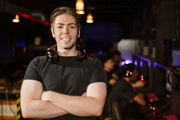 Smiling gamer standing with headphones in an illuminated gaming arena.