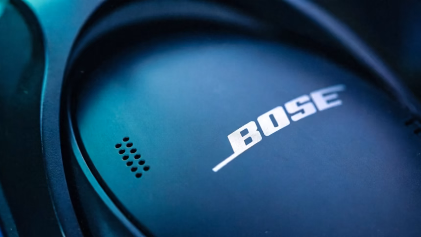 A pair of modern wireless headphones resting on a desk next to an older wired model, illustrating the evolution of audio gear.